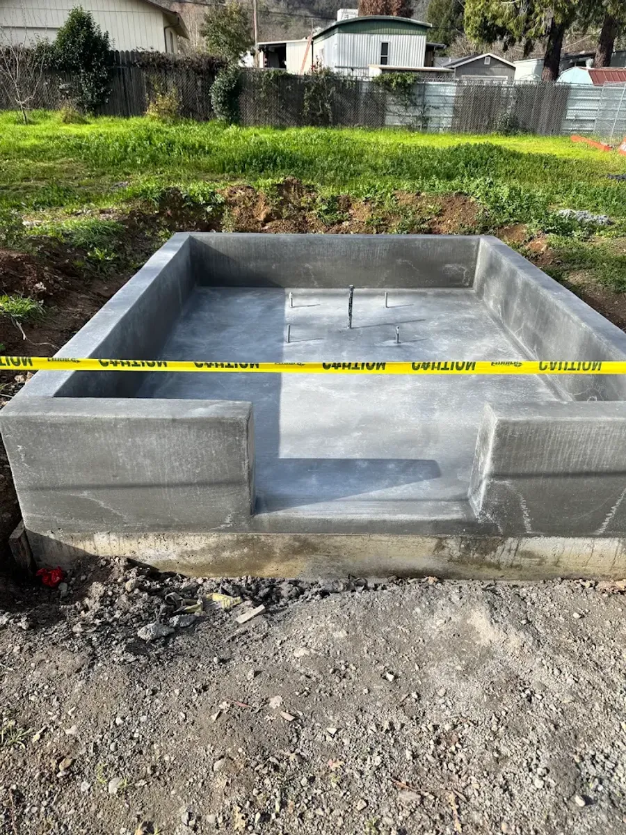 Small rectangular concrete foundation with service pipes