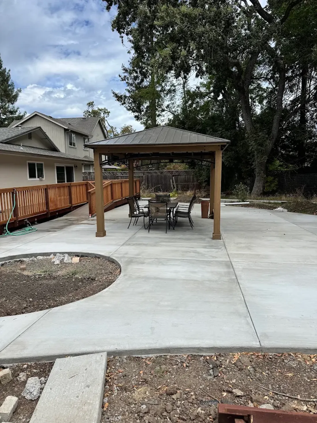 Finished curved concrete patio around a backyard pergola