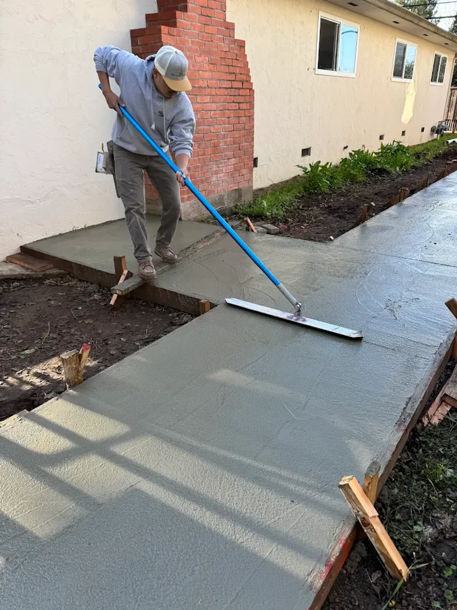 Worker finishing a newly poured concrete path