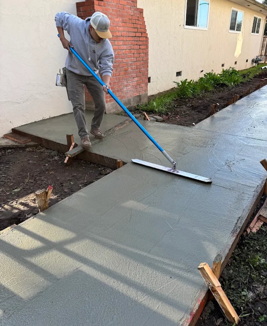 Concrete being finished by hand along a side-yard path