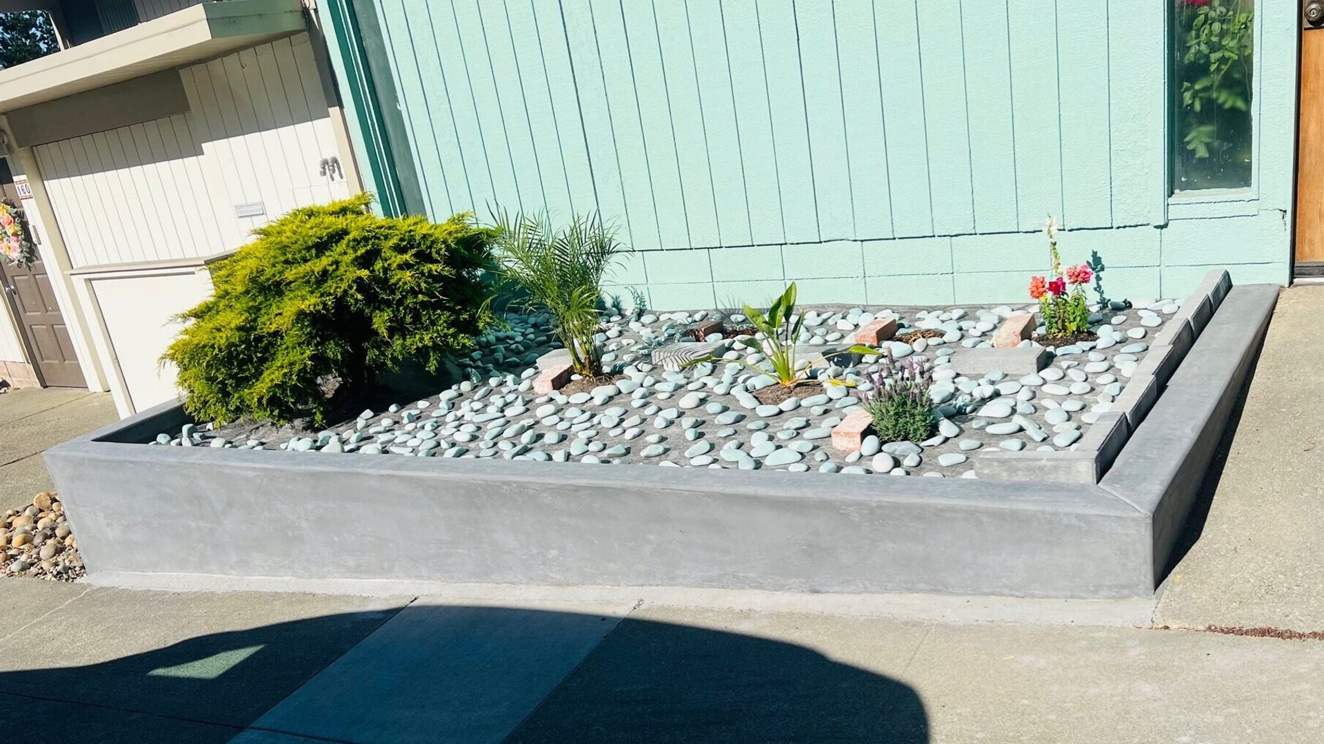 Concrete landscape wall and finished paving beside a home
